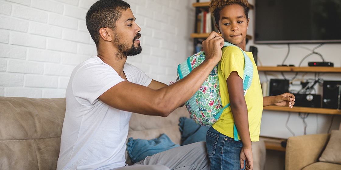 Father putting on his son's backpack