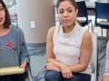 Two mothers sitting next to each other in a meeting. The mother on the left is talking while holding a legal pad in her lap.