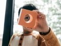 Young child looking at the camera through a square foam block with a circle cut out of the center.