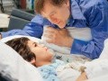 Father speaking to his son as the son lies in a hospital bed