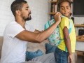 Father putting on his son's backpack