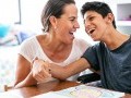 Mom and son smiling: son has a physical disability and is seated in a wheelchair.